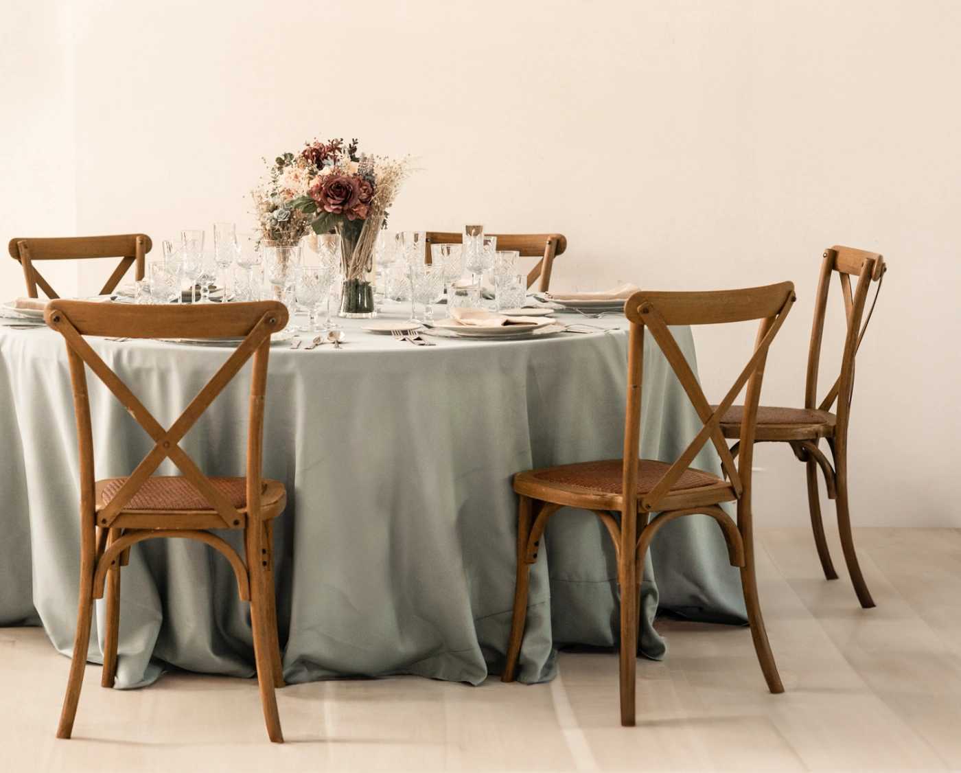 Alquiler de sillas Crossback de madera y mesas redondas con mantelería verde para eventos en Sevilla.
